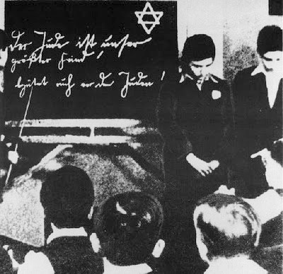 Ca. 1935: Two Jewish pupils are humiliated before their classmates. The inscription on the blackboard reads 